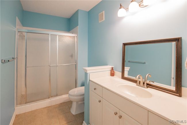 Bathroom with a stall shower, visible vents, vanity, and toilet | Image 9