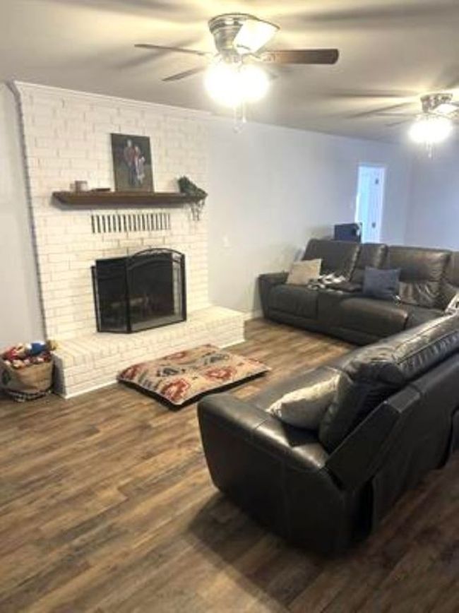 Living room featuring wood finished floors, ceiling fan, and a fireplace | Image 8