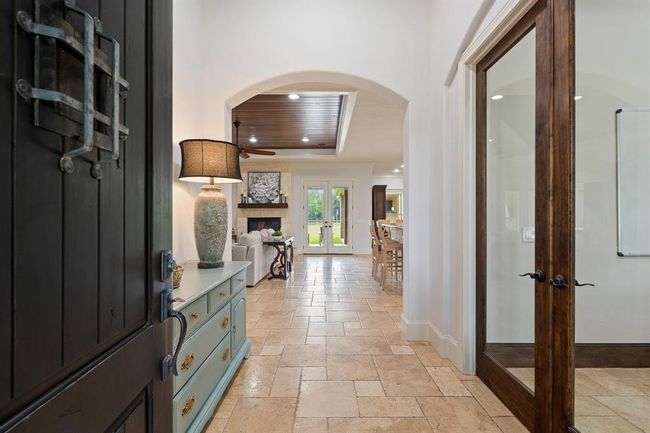 Upon entering the home, friends and family are greeted by a warm and inviting color pallet, high-end Versailles patterned tumbled Travertine flooring, and an elegant arched walkway. The eyes are immediately drawn toward the glass-paned double doors at the back of the home, and the picturesque views that await. | Image 5