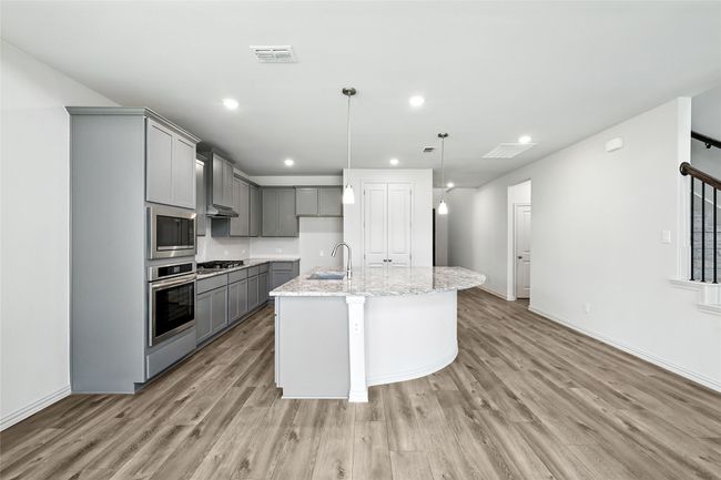 Kitchen featuring gray cabinetry, appliances with stainless steel finishes, light wood-style floors, light stone countertops, and recessed lighting | Image 8