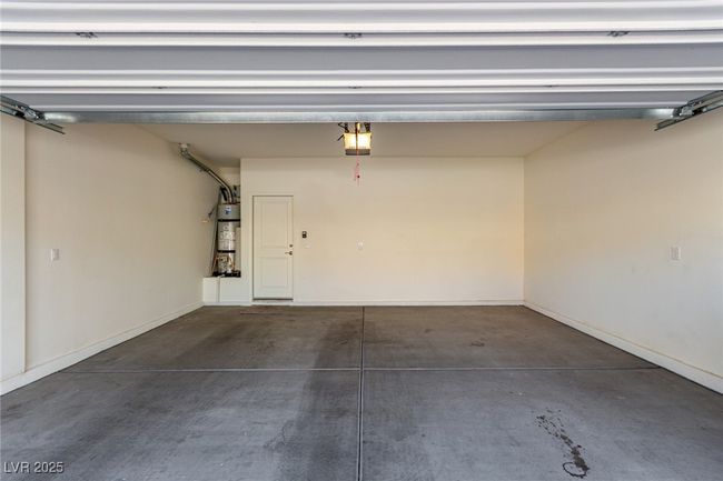 Garage featuring baseboards, secured water heater, and a garage door opener | Image 27