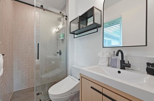 The primary ensuite bathroom comes fully remodeled with a spa-like walk-in shower wrapped in unique designer backsplash and frameless glass sliders. | Image 24