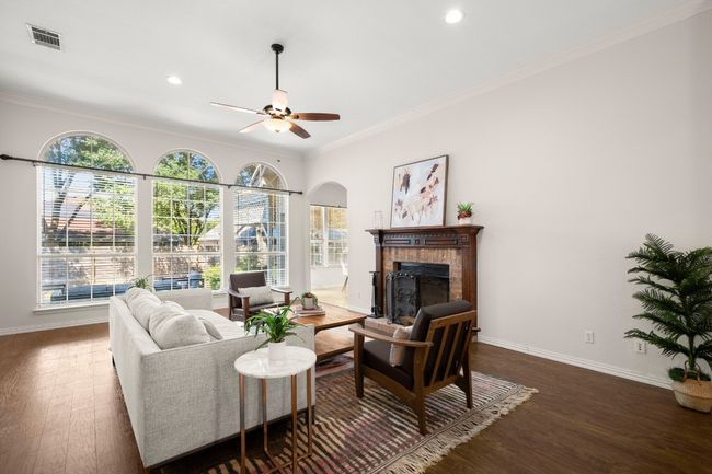 Living room featuring ornamental molding, healthy amount of natural light, dark wood finished floors, a brick fireplace, and ceiling fan | Image 9
