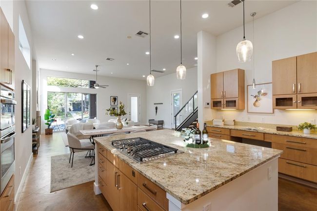 Kitchen featuring stainless steel gas stovetop, open floor plan, a kitchen island, recessed lighting, and ceiling fan | Image 17