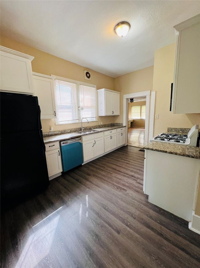 Kitchen with dishwasher, freestanding refrigerator, dark wood-style floors, and healthy amount of natural light | Image 15