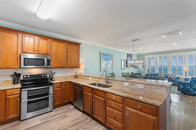 Kitchen with stainless steel appliances, a peninsula, and light wood-style floors | Image 14