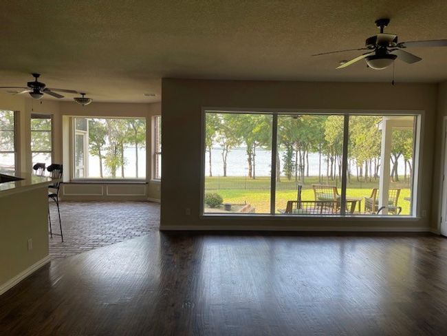 Unfurnished living room with dark wood finished floors, ceiling fan, and a healthy amount of sunlight | Image 15