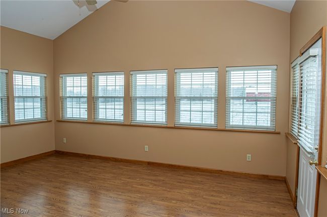 Spare room with high vaulted ceiling, baseboards, light wood-style floors, and ceiling fan | Image 5