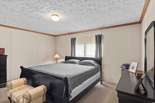 Carpeted bedroom featuring ornamental molding, a textured ceiling, and a decorative wall | Image 31
