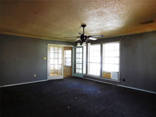 Carpeted spare room featuring a textured ceiling, cooling unit, ceiling fan, and ornamental molding | Image 16