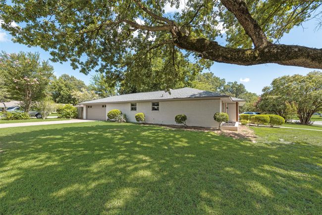 View of property exterior featuring a yard, concrete driveway, and a garage | Image 4