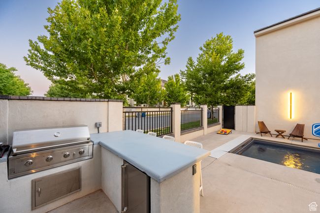 Patio terrace at dusk with grilling area, a fenced in pool, and area for grilling | Image 27