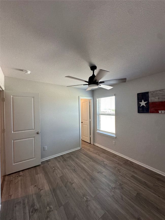 Unfurnished bedroom featuring ceiling fan, baseboards, wood finished floors, and a textured ceiling | Image 14