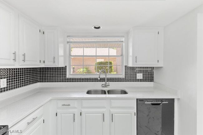 Kitchen with black dishwasher, sink, tasteful backsplash, and white cabinets | Image 15