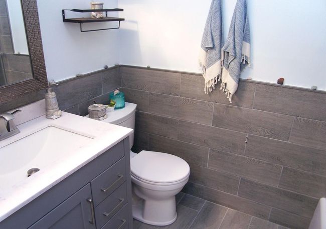 Bathroom featuring toilet, tile walls, vanity, a wainscoted wall, and wood finished floors | Image 8