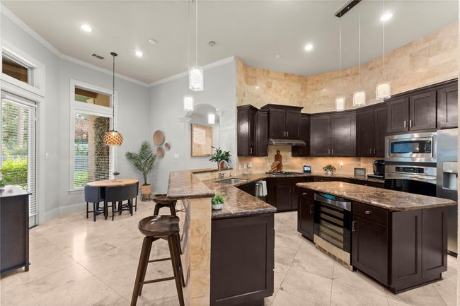 The breakfast room is just off the chef’s kitchen, which is a culinary masterpiece featuring high-end stainless steel appliances, expansive countertops, and abundant custom cabinetry designed for optimal organization. | Image 17