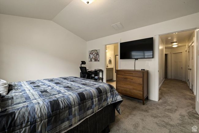 Bedroom with visible vents, vaulted ceiling, carpet floors, and connected bathroom | Image 16
