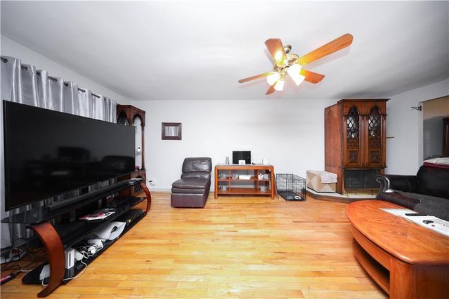 Living room featuring light wood-type flooring and ceiling fan | Image 6
