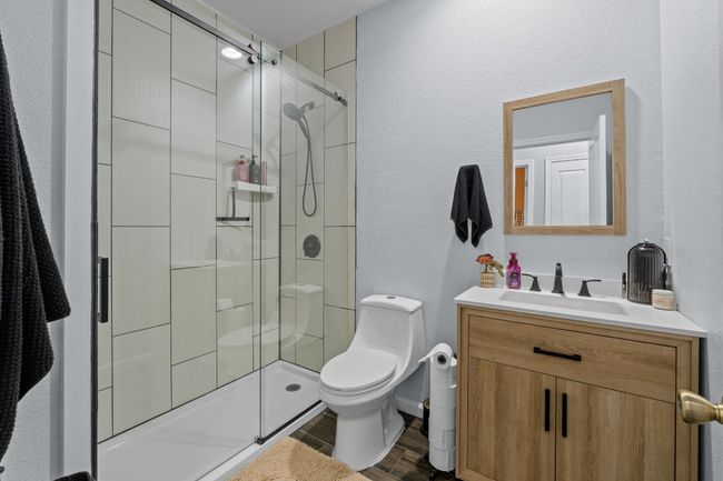 Bathroom with vanity, toilet, wood finished floors, a stall shower, and a textured wall | Image 26