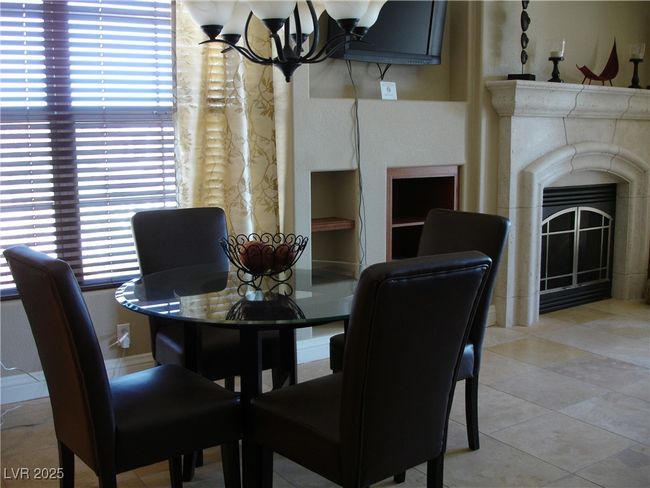 Dining area with a chandelier, a fireplace, and light tile patterned floors | Image 5