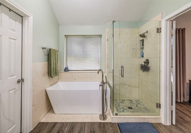 Full bath featuring a soaking tub, a textured ceiling, a shower stall, and wood finished floors | Image 24