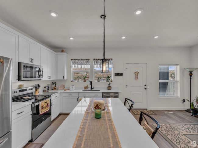 Kitchen with stainless steel appliances, a sink, light countertops, decorative light fixtures, and recessed lighting | Image 7