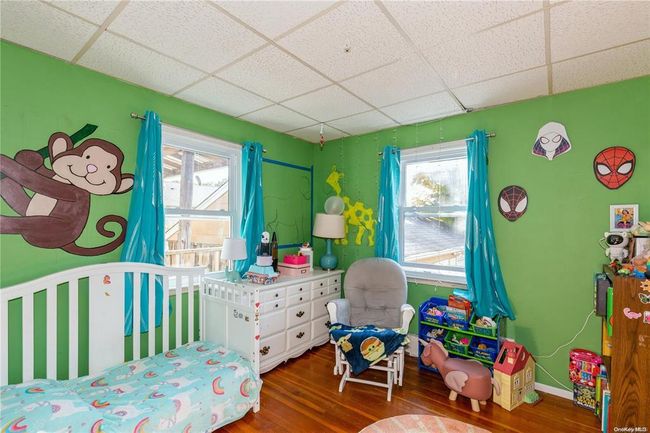 Bedroom with wood finished floors, a drop ceiling, baseboards, and multiple windows | Image 11