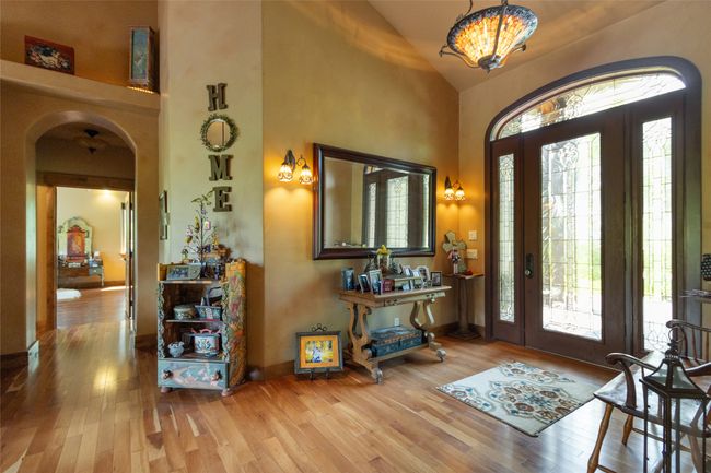 Entryway featuring arched walkways, wood finished floors, high vaulted ceiling, and a chandelier | Image 27