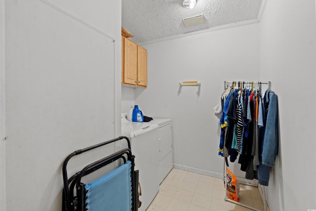 Washroom with washer and clothes dryer, cabinet space, a textured ceiling, and crown molding | Image 28