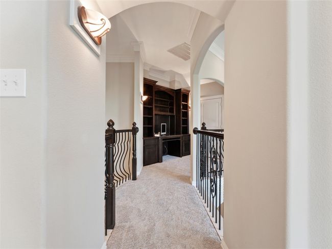 Hallway featuring ornamental molding, arched walkways, light colored carpet, and an upstairs landing | Image 35