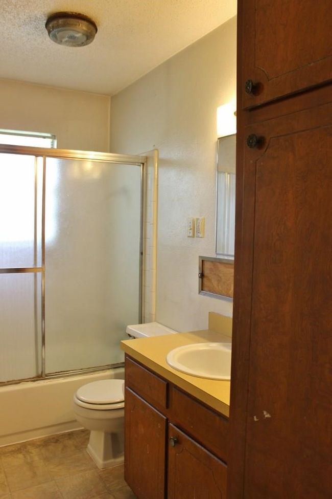 Bathroom featuring vanity, bath / shower combo with glass door, and a textured ceiling | Image 6