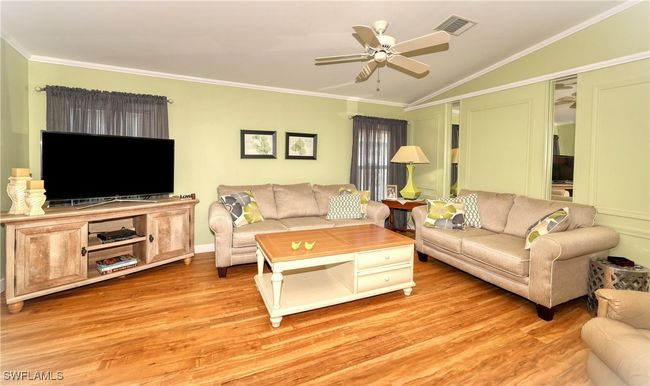 Living room featuring ceiling fan, light hardwood / wood-style flooring, vaulted ceiling, and ornamental molding | Image 13