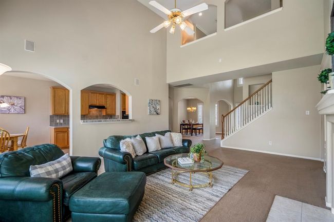 From the back wall of the family room, you get a glimpse into the breakfast nook and kitchen area. The formal dining room is visible through the arched doorways near the front of the home, while the arched openings above the staircase lead to the upstairs landing, adding an elegant touch to the space. | Image 10
