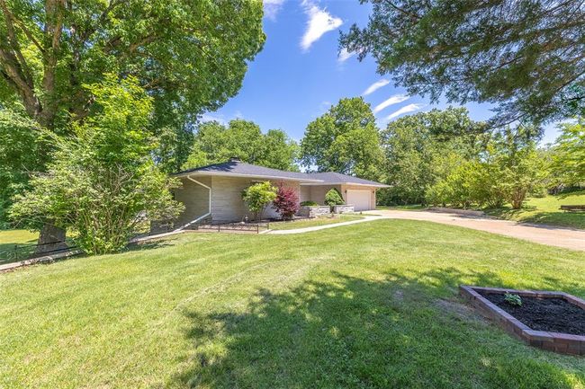 View of front facade featuring concrete driveway, a garage, a front lawn, and a chimney | Image 23