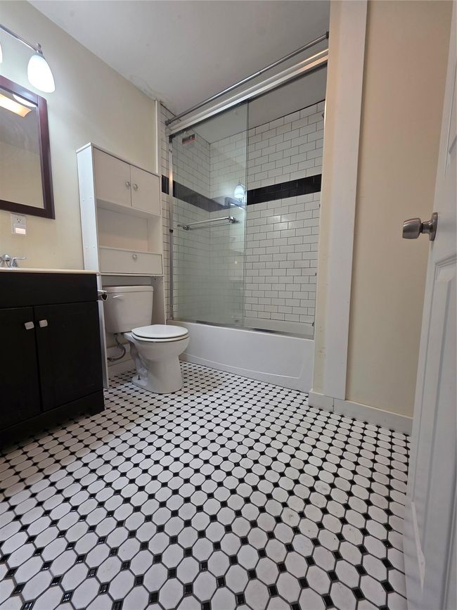 Bathroom featuring toilet, bath / shower combo with glass door, vanity, and tile patterned floors | Image 8