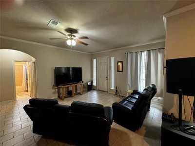 Living room with a textured ceiling, ceiling fan, and crown molding | Image 3