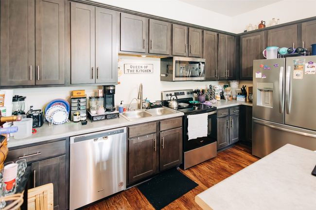 Kitchen featuring stainless steel appliances, light countertops, dark brown cabinetry, and dark wood finished floors | Image 5