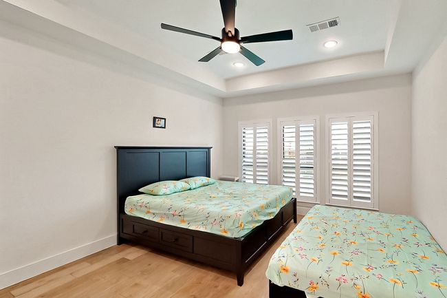 Bedroom with a raised ceiling, light wood finished floors, baseboards, a ceiling fan, and recessed lighting | Image 18