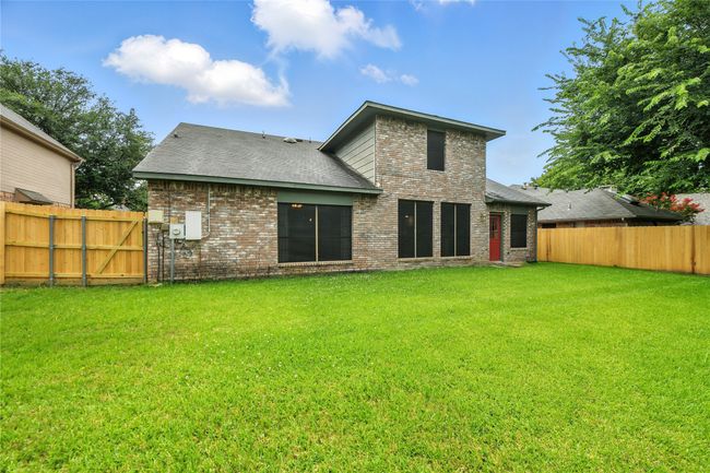 Rear view of property featuring brick siding, a fenced backyard, and roof with shingles | Image 35