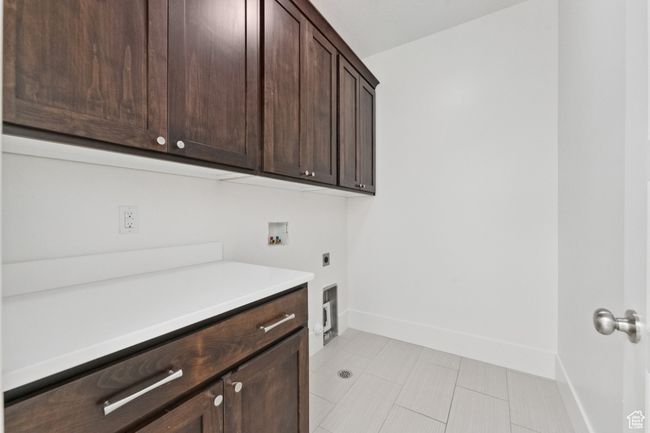 Laundry room with hookup for an electric dryer, hookup for a washing machine, cabinet space, and light tile patterned floors | Image 11