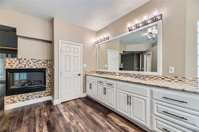 Bathroom featuring double vanity, wood finished floors, backsplash, and a tile fireplace | Image 23