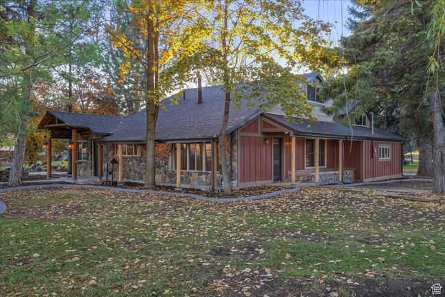 Back of house with a lawn, stone siding, board and batten siding, and a shingled roof | Image 7