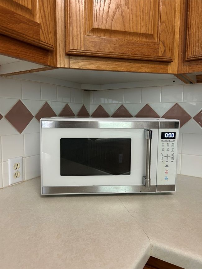 Kitchen view of brown cabinets, light countertops, and backsplash | Image 9