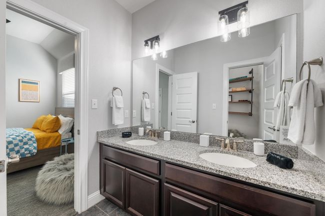 This shared bathroom has a generously sized walk-in closet, dual vanities and stylish industrial lighting. | Image 31