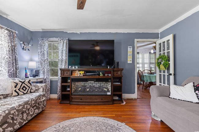 Living area with a ceiling fan, wood finished floors, and ornamental molding | Image 11