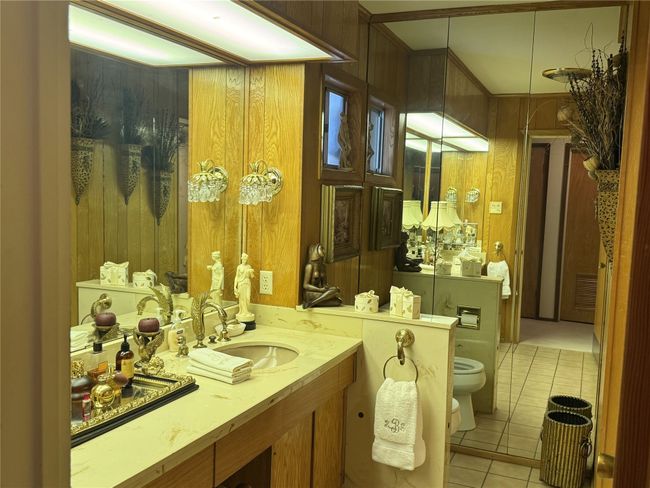 Bathroom with tile patterned floors, toilet, vanity, wood walls, and a bidet | Image 37