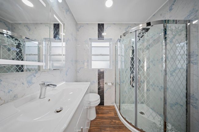 Bathroom featuring wood finished floors, toilet, a stall shower, and vanity | Image 20