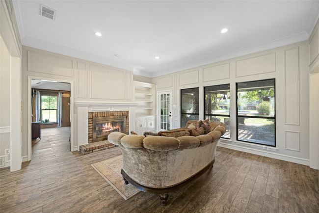 Living area featuring visible vents, a fireplace, crown molding, recessed lighting, and wood finished floors | Image 9