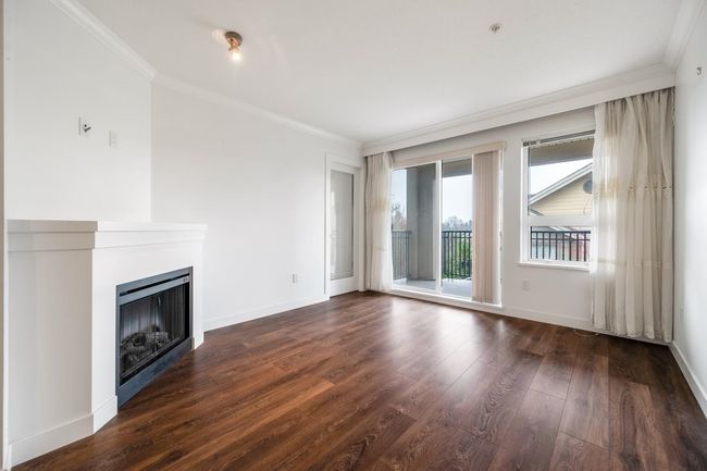 Unfurnished living room with crown molding, dark wood-style floors, and a fireplace | Image 6