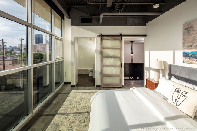Bedroom featuring wood finished floors, a barn door, and a city view | Image 11